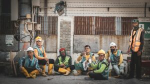 Group of construction workers in safety gear taking a break at an urban site.